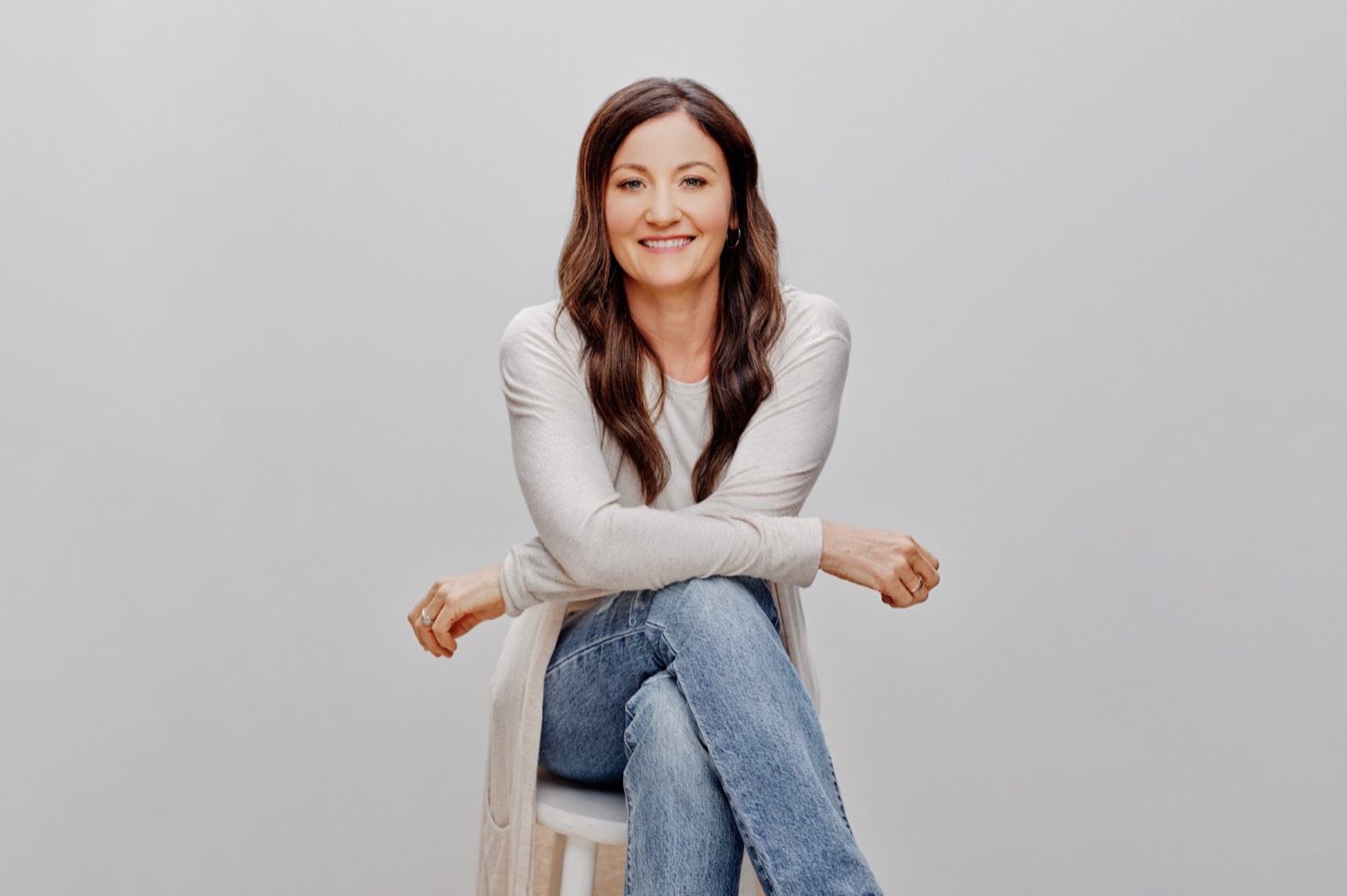 Portrait of April Macdonald seated on a stool, smiling